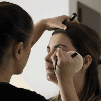 Make-up-Behandlung, bei der ein Make-up-Artist das Make-up einer Frau aufträgt.
